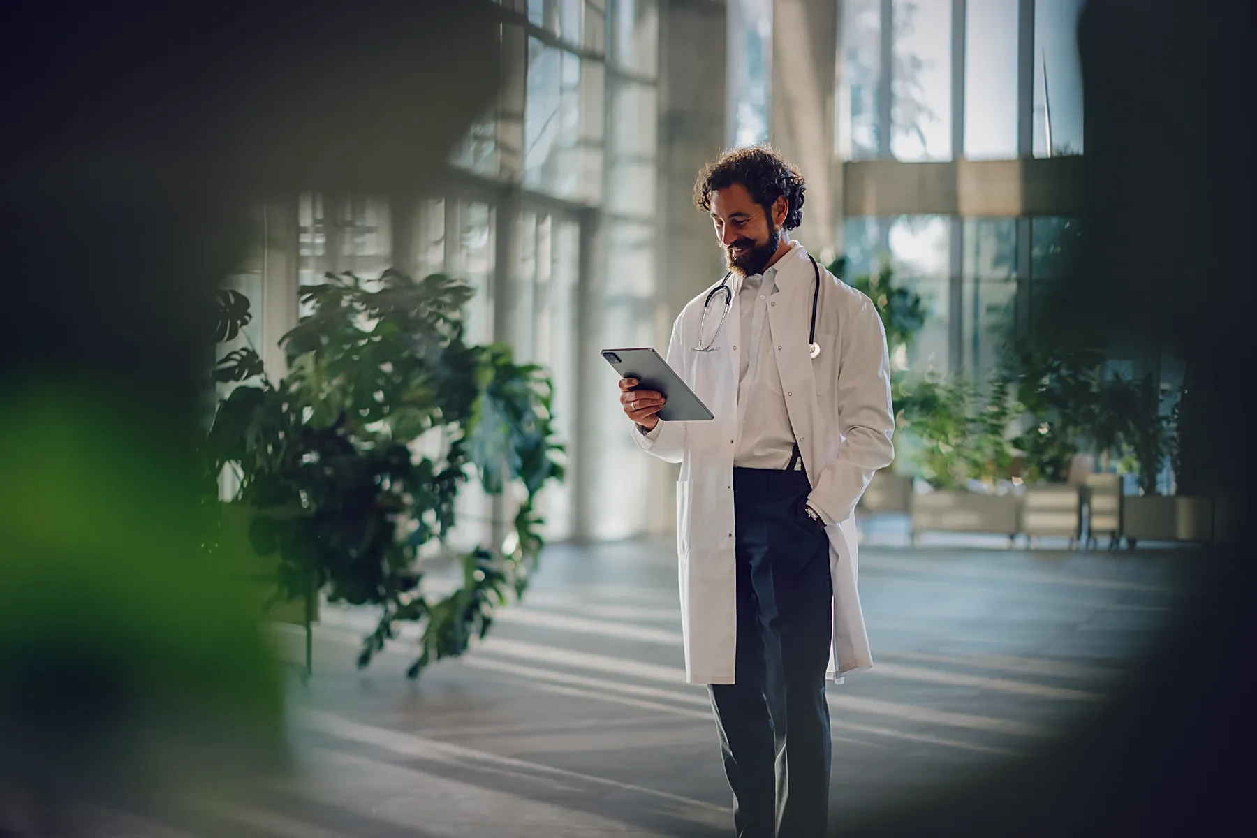 A surgeon checking a case on a tablet in a bright hospital atrium